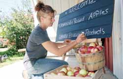 Lisa Rettinger prepares the welcome sign at Grandview Orchard Friday afternoon.