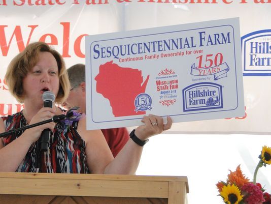 Jyme Buttke, Executive Secretary of Wisconsin Association of Fairs held up the sign the Sesquicentennial Farm families would be receiving at the conclusion of the special breakfast in their honor at Wisconsin State Fair. Century Farm families also received signs.
(Photo: Gloria Hafemeister)