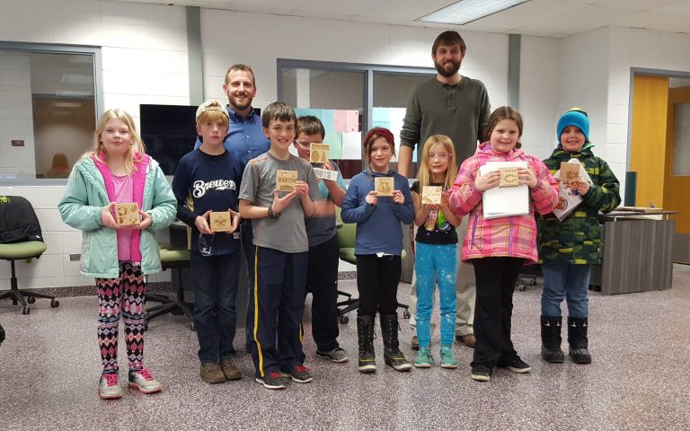 Andy Bauknecht from Rexnord-Merit Gear (back left) and Tim Krueger, AHS Fab Lab Coordinator (back right) post with the Elementary STEM Scouts and their finished projects.